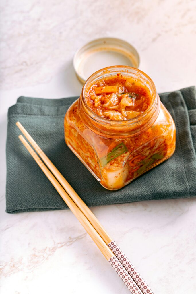 Kimchi in a glass jar with chopsticks — fermented foods support gut microbiome diversity