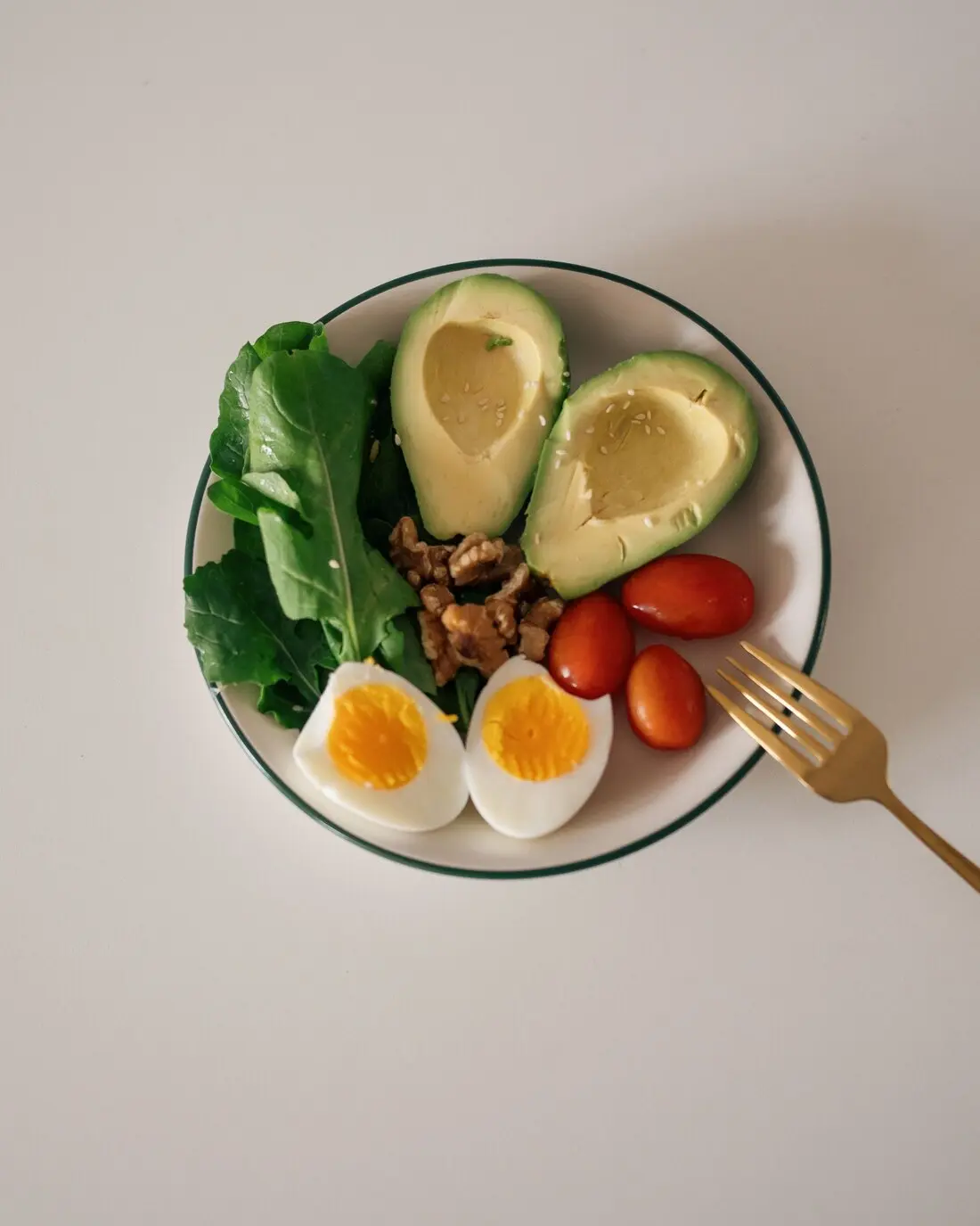 A Mediterranean-style plate with leafy greens, avocado, walnuts, cherry tomatoes and a boiled egg — an example of IVF-friendly eating
