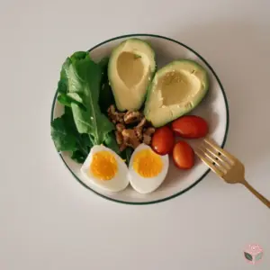 A plate of avocado, eggs, walnuts, tomatoes and greens