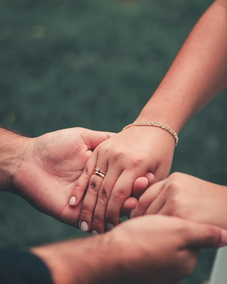 Close-up of a couple holding hands in warm light — most women with endometriosis who become pregnant have a healthy baby